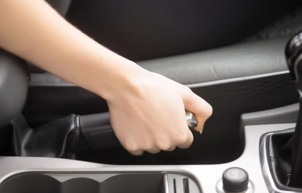 hamulec-reczny Mechanik regulujący hamulec postojowy w samochodzie – widok na podwozie w serwisie
